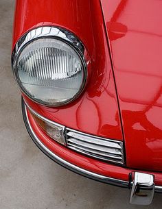 the front end of a red car with its lights turned on and headlight showing