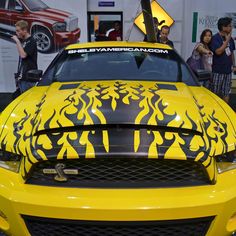 a yellow mustang with black flames painted on it