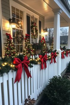 christmas decorations on the front porch of a house with red bows and lights around them