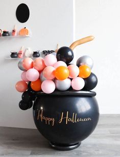 a large black pot filled with balloons on top of a wooden floor