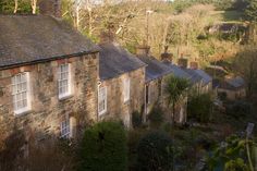 an old stone house with trees and bushes around it