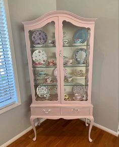 a pink china cabinet with plates on it