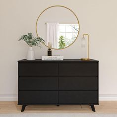 a black dresser with a round mirror on top and plants in vases next to it