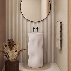 a round mirror hanging on the wall next to a white vase with flowers in it