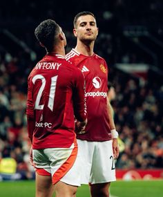 two men standing next to each other on a soccer field