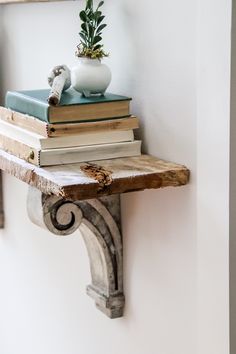 a stack of books sitting on top of a wooden shelf next to a potted plant