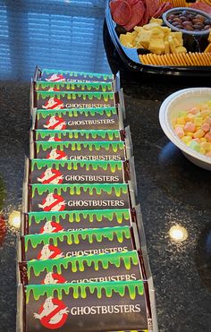 several boxes of ghostbusters candy sitting on a counter next to plates of food