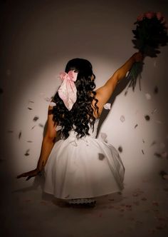 a woman in a white dress is holding flowers and throwing confetti into the air