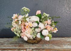 a vase filled with lots of flowers on top of a wooden table next to a wall