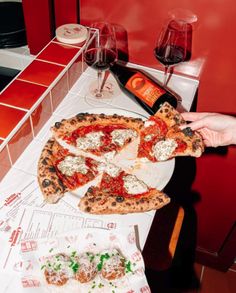 a person holding up a pizza on top of a table