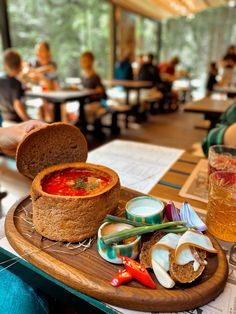 a wooden tray topped with lots of food on top of a table next to people