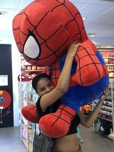 a woman is hugging a giant stuffed spider man