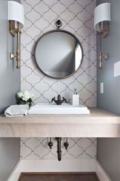 a white sink sitting under a mirror in a bathroom next to a wall mounted faucet