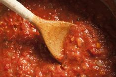 a wooden spoon in a pot filled with red sauce and tomato sauce on the side