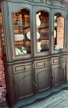 an antique china cabinet with glass doors on the top and bottom, painted in black