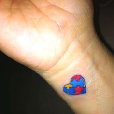 a person's wrist with a colorful piece of puzzle on the left side of their arm