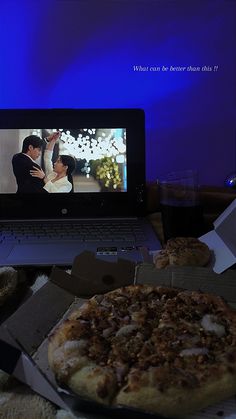 a laptop computer sitting on top of a desk next to a pizza and cup filled with liquid