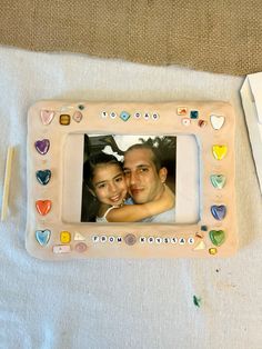 a man and woman are holding each other in front of a picture frame with hearts on it