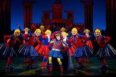 a group of people standing on top of a stage in front of red and blue outfits