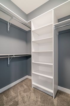 an empty walk - in closet with shelves and hanging rails on the wall, along with carpeted flooring