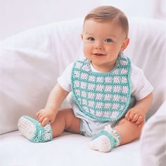 a baby sitting on a couch wearing a bib and booties