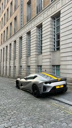 a silver and yellow sports car parked on the side of a road next to a building