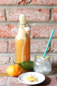 an orange juice in a glass bottle next to two small plates with fruit on them