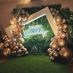 an image of a happy birthday sign surrounded by balloons and greenery on the floor