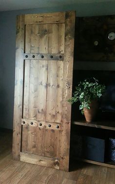 an open wooden door in the corner of a room next to a potted plant