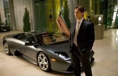 a man in a suit standing next to a sports car