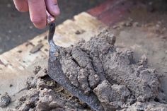 a person is shoveling dirt into a pile with a metal spoon in their hand