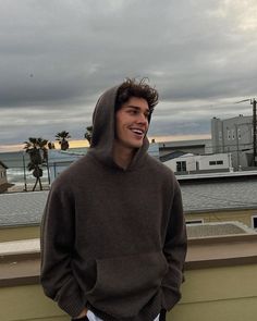 a young man standing on top of a roof next to a building and looking off into the distance