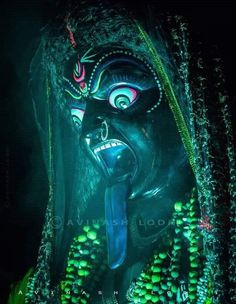 an elaborately decorated mask is lit up in the dark with bright green beads around it