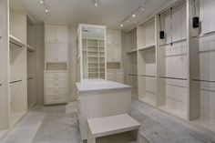 an empty walk in closet with lots of white cabinets and drawers on either side of the room