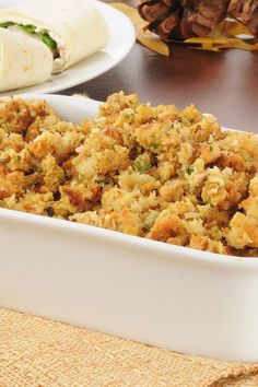 a casserole dish filled with stuffing on top of a table next to cupcakes