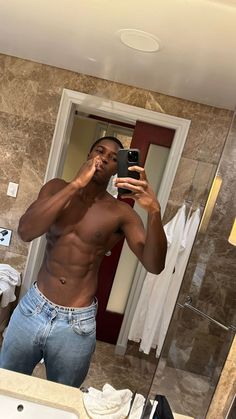 a shirtless man taking a selfie in the bathroom mirror with his cell phone