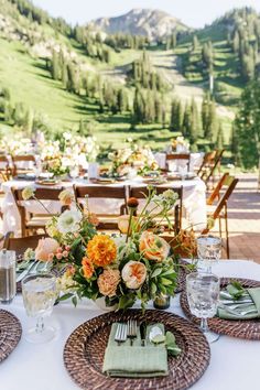 a table set with place settings and flowers in the center for an outdoor wedding reception