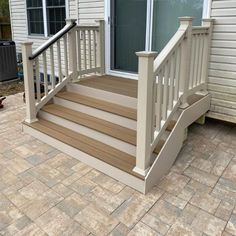 a white porch with steps leading up to the front door and patio area next to it