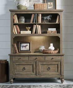 an old bookcase with books and pictures on the top, next to a vase