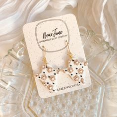 a pair of earrings sitting on top of a glass tray next to a white cloth