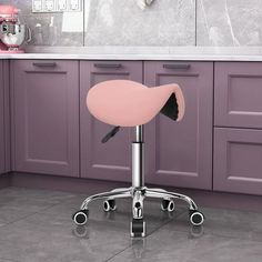 a pink stool sitting in front of a kitchen counter with purple cabinets and white counters