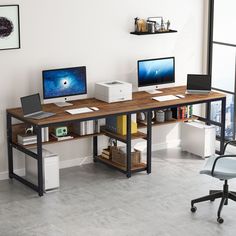 two computer monitors sitting on top of a wooden desk in front of a white wall