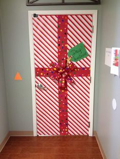 a door decorated with a red and white striped christmas present tied to it's side