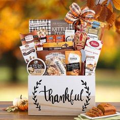 a thank you gift box filled with food and snacks on a table in front of fall leaves