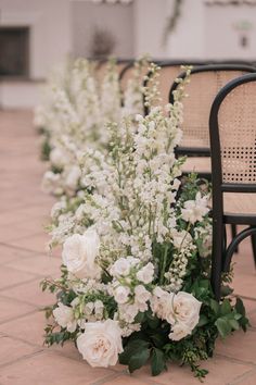 white flowers and greenery are lined up on the ground