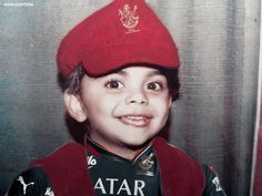 a young boy wearing a red hat and smiling at the camera with his name written on it