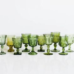 a group of green glass goblets sitting on top of a white table next to each other