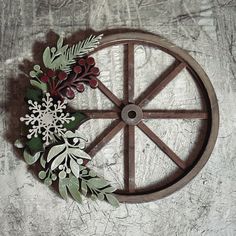 a wooden wheel with flowers and leaves on it sitting on a table next to a wall