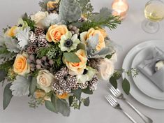 a bouquet of flowers sitting on top of a table next to plates and silverware