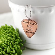 a wooden guitar pick sitting on top of a table next to a green flower pot